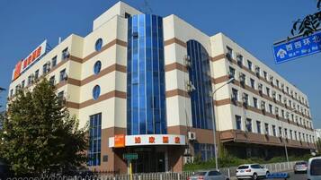 Un hotel con fachada moderna, que destaca una amplia sección vertical de vidrio y múltiples ventanas.