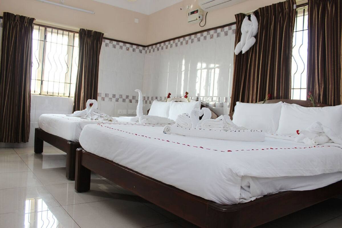 A hotel room with two beds, a large window with curtains, and a decorative swan on the wall.