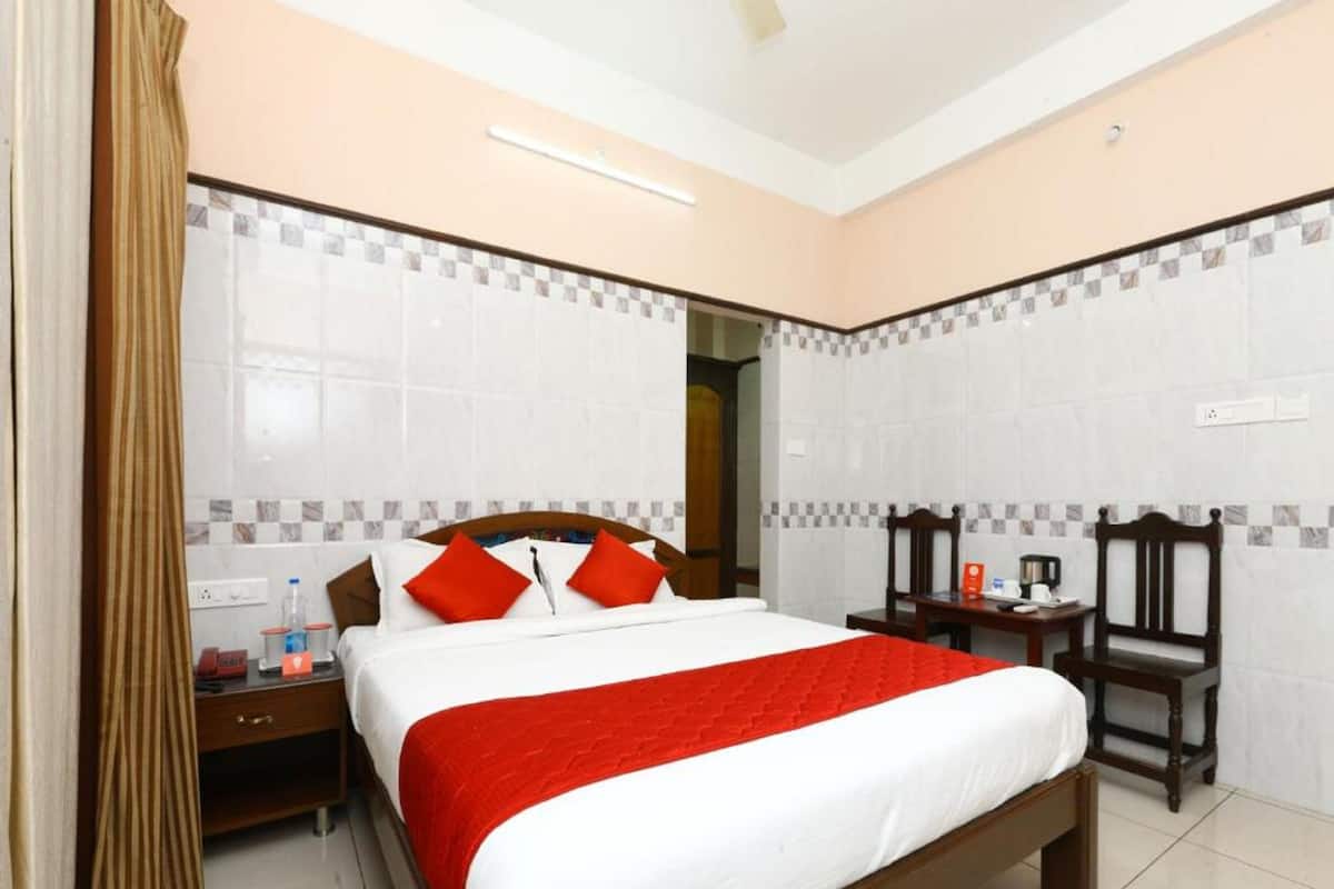 A hotel room with a large bed, a bedside table, a chair, and a desk.