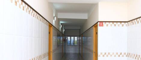 A corridor with tiled walls and a patterned floor, leading to a door with a red 'X' sign.