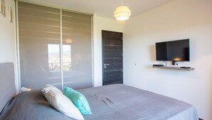 Ein Schlafzimmer mit Bett, einem an der Wand befestigten Fernseher und einer Schiebetür.