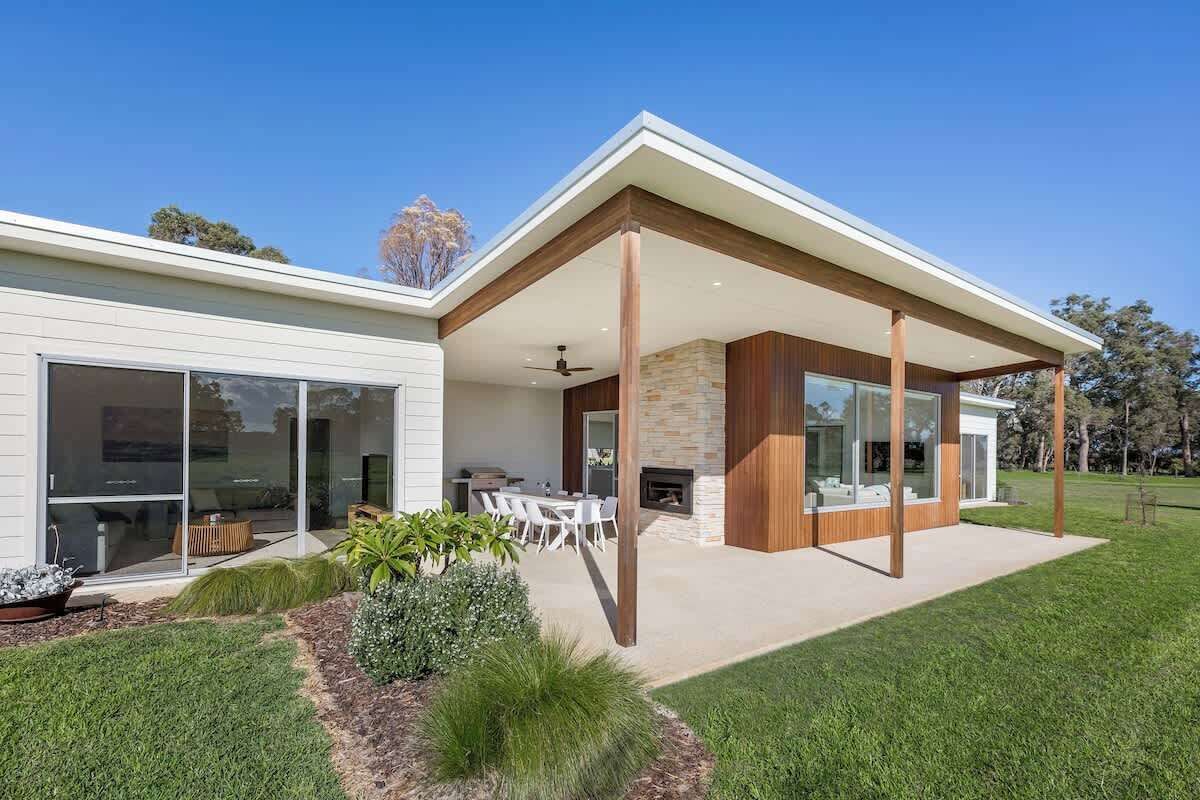 A modern house with a patio, outdoor seating, and a stone fireplace.
