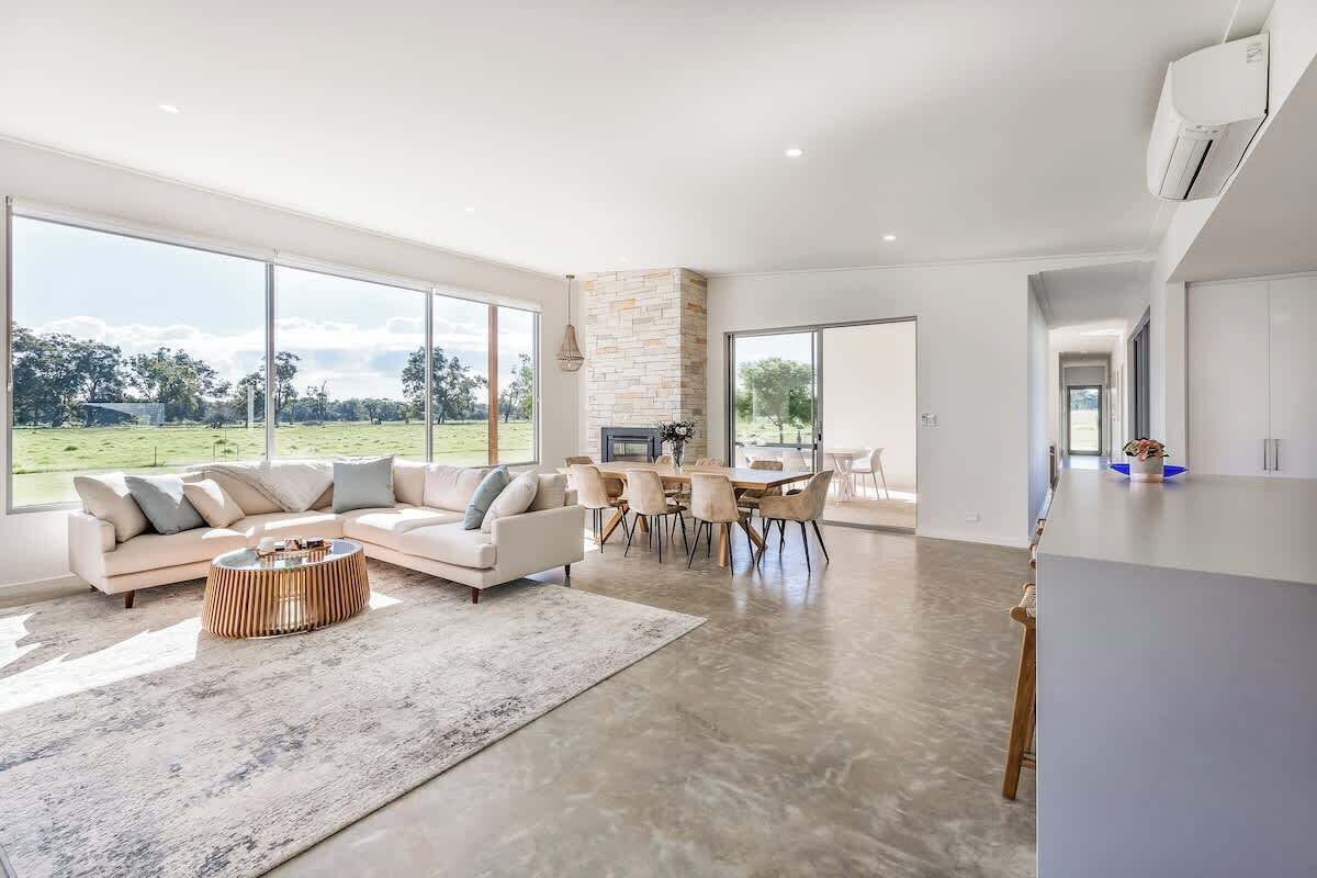 A spacious living area with a large window, a stone fireplace, and a dining area.