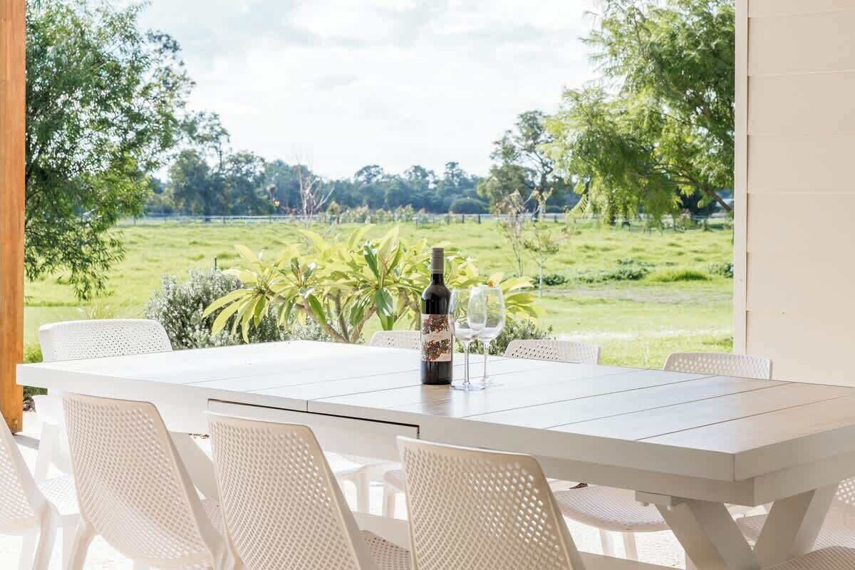 A dining table with six chairs, a bottle of wine, and two wine glasses.