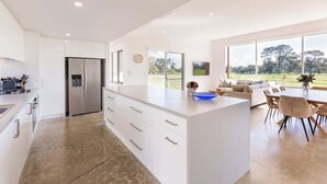 Una cocina moderna con una isla grande, un comedor con vistas y un espacio de sala con sofá y sillas.