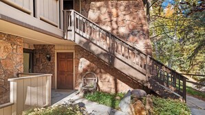 A stone staircase leading to a wooden door, surrounded by greenery and a stone wall. - Aspen Stash Pad Steps From The Slopes (Aspen)