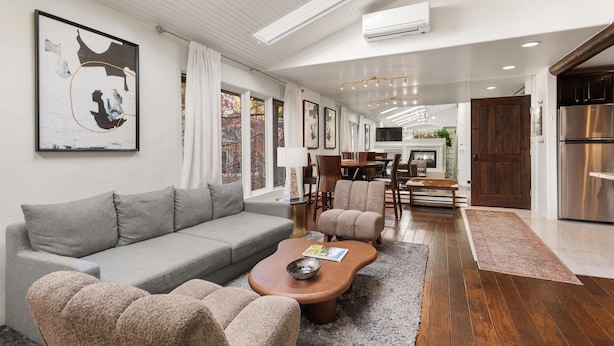 A modern living room with a grey sofa, beige armchairs, a wooden coffee table, and a large abstract painting on the wall. - Aspen Stash Pad Steps From The Slopes (Aspen)