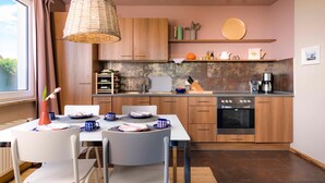 A modern kitchen with wooden cabinets, a built-in oven, and a dining area with a table set for two. - Lake House - Pomeranian-style house by the lake with a lake view, sauna, fireplace, and rowboat (Luckow)