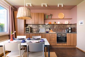 A modern kitchen with wooden cabinets, a built-in oven, and a dining area with a table set for two.