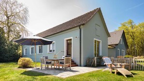 Une maison avec un patio, une table, des chaises et un parasol.