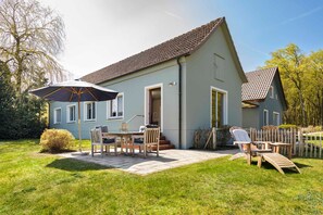 A house with a patio, a table, chairs, and an umbrella.