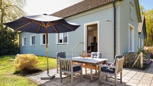 A patio with a table and chairs, an umbrella, and a small garden. - Lake House - Pomeranian-style house by the lake with a lake view, sauna, fireplace, and rowboat (Luckow)