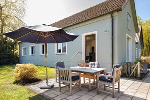 A patio with a table and chairs, an umbrella, and a small garden.