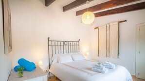 Een slaapkamer met een bed, nachtkastjes, een hanglamp en een raam met gordijnen.