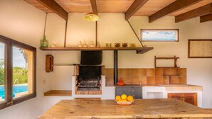 Een rustieke keuken met een grote houten tafel, een inbouwoven en uitzicht op een zwembad.