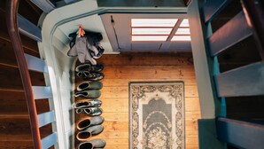 Una scala con un mobiletto per scarpe a sinistra e un tappeto decorato sul pavimento.