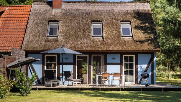 A thatched-roof house with a patio, outdoor seating, and a barbecue. - Pommernhaus Vorsee am Kiefernwald Kamin Boot - Thatched half-timbered house, fireplace (Ahlbeck)