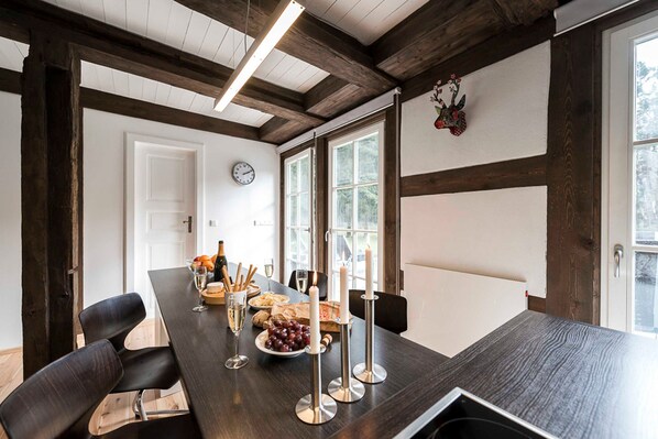 Un espace repas avec une longue table, des chaises, des bougies et une horloge au mur.