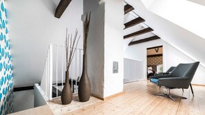 A spacious loft with high ceilings, exposed wooden beams, and a large window providing natural light. - Pommernhaus Vorsee am Kiefernwald Kamin Boot - Thatched half-timbered house, fireplace (Ahlbeck)