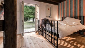 A bedroom with a bed, a view of the outdoors, and a wooden floor. - Pommernhaus Vorsee am Kiefernwald Kamin Boot - Thatched half-timbered house, fireplace (Ahlbeck)