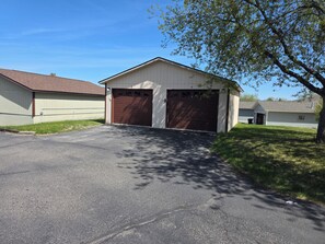 A single-story building with a garage, a paved driveway, and a grassy area.
