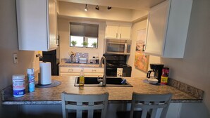 A modern kitchen with a granite countertop, stainless steel appliances, and white cabinetry. - Lee's Helena Hideout (Helena)