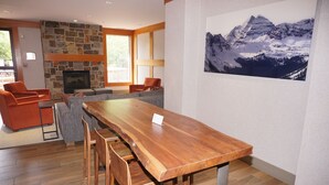 Ein modernes Wohnzimmer mit Kamin aus Stein, Holzesstisch und gemütlicher Sitzgelegenheit.