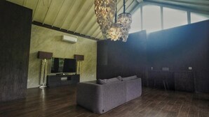 A spacious living room with a large grey sofa, a flat-screen TV, and a unique chandelier. - Sandhya Villa Ubud (Payangan)