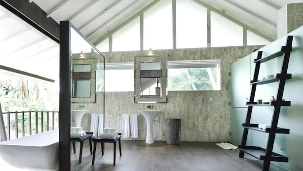 A modern bathroom with a freestanding bathtub, two sinks, a large mirror, and a black metal shelf unit. - Sandhya Villa Ubud (Payangan)