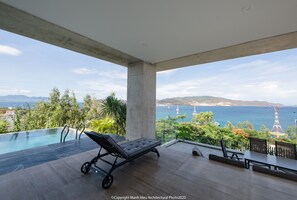 A modern outdoor lounge area with a pool, a lounge chair, and a table.