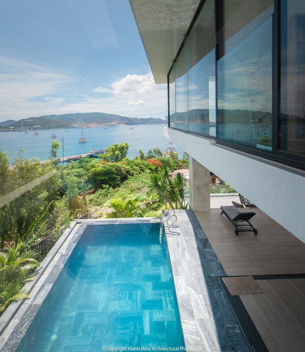 A modern pool with a clear view of the sea and mountains in the background.