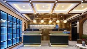 A hotel reception area with a modern design, featuring a reception desk, a seating area, and a decorative ceiling. - Nostalgia S Hotel (Beijing)