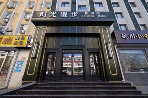 A hotel entrance with a sign for 'Nostalgia Hotel' and a staircase leading up to the doors. - Nostalgia S Hotel (Beijing)