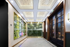 A hallway with a modern elevator, a large glass wall with a cityscape, and a door with a window. - Nostalgia S Hotel (Beijing)