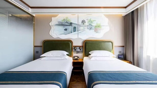 A hotel room with two beds, a wall-mounted artwork, a telephone, and a nightstand. - Nostalgia S Hotel (Beijing)