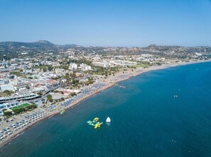An aerial view of a coastal city with a beach, buildings, and boats. - Faliraki Premium Hotel (Rhodes)