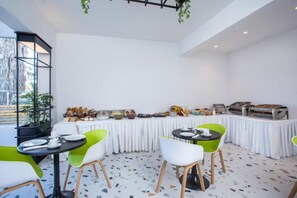 A dining area with round tables, chairs, and a buffet with various food items. - Faliraki Premium Hotel (Rhodes)