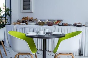 A breakfast buffet setup with a table, chairs, and various food items. - Faliraki Premium Hotel (Rhodes)