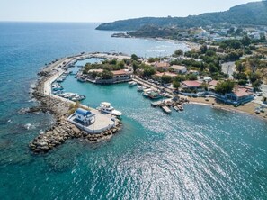 A coastal marina with boats docked, a small island with a building, and a town in the background. - Faliraki Premium Hotel (Rhodes)