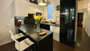 Una cucina moderna con isola centrale, pensili bianchi e piano di lavoro nero. Sull'isola, un vaso con fiori gialli e un orologio a parete.