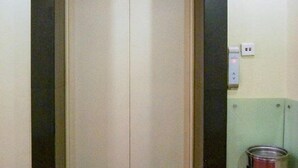 Puerta cerrada de ascensor con interruptor de luz y toma de corriente en la pared.