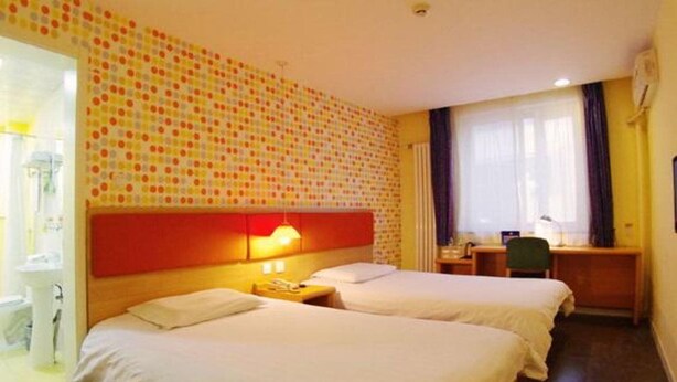 Habitación de hotel con dos camas, un escritorio, una silla, un teléfono y un baño visible a través de una puerta abierta.