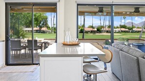 Et moderne køkken med en stor ø, skydedøre til en terrasse og udsigt til en golfbane.