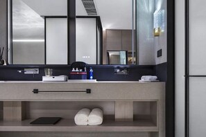 A modern bathroom with a large mirror, a towel rack, a sink, and a shelf with toiletries. - Mehood Elegant Hotel Qianjiang (Hangzhou)