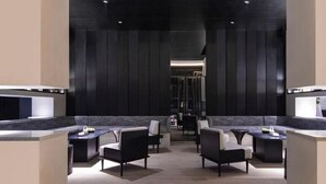 A modern, dimly lit lobby with a central seating area featuring sofas and tables, flanked by dark paneling and a reflective floor. - Mehood Elegant Hotel Qianjiang (Hangzhou)