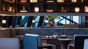 A modern lounge area with seating, a coffee table, and a bookshelf with books and decorative items. - Mehood Elegant Hotel Qianjiang (Hangzhou)