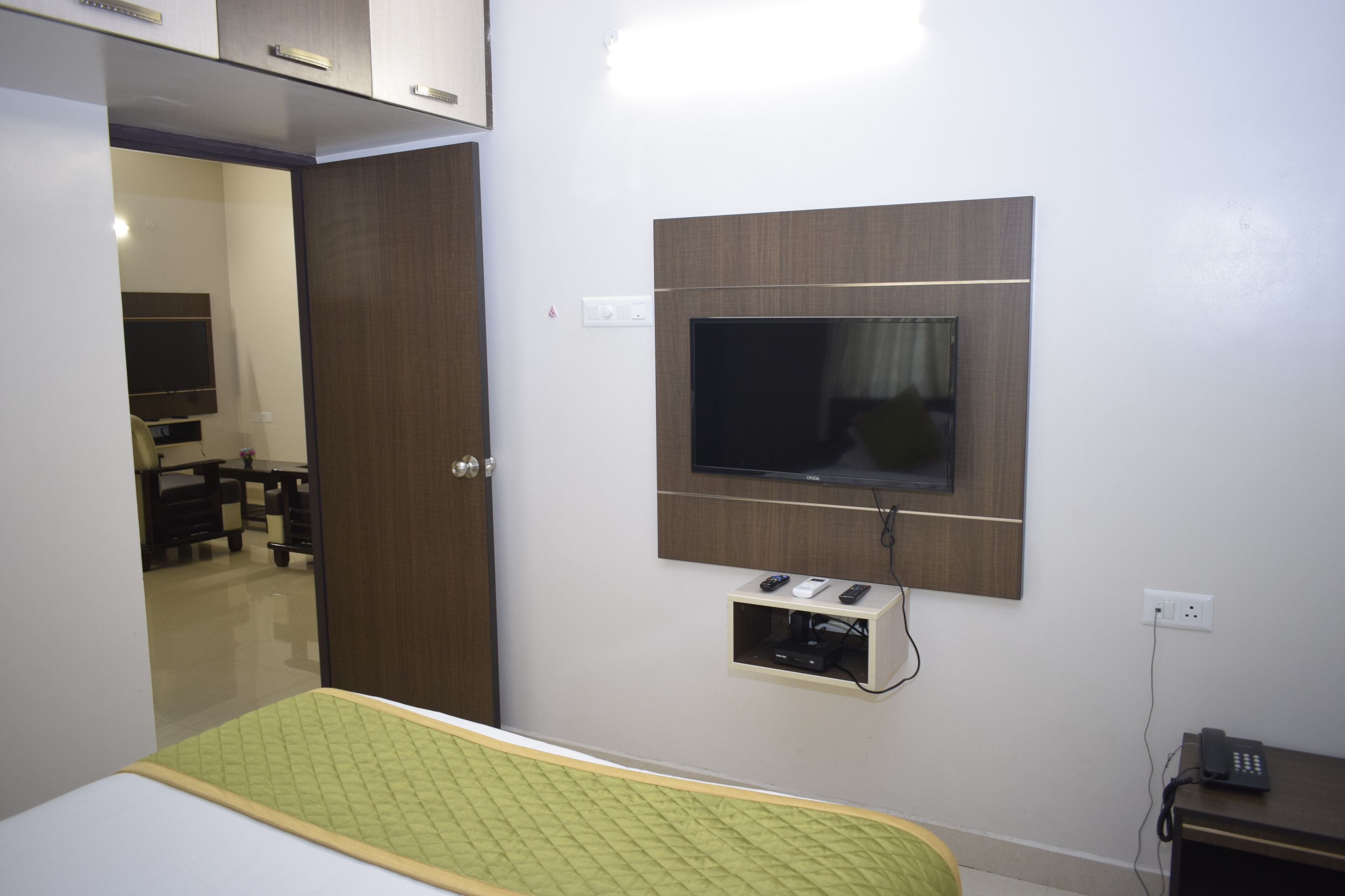 Une chambre à coucher comprenant un lit, un téléviseur fixé au mur, une table de chevet et une armoire.