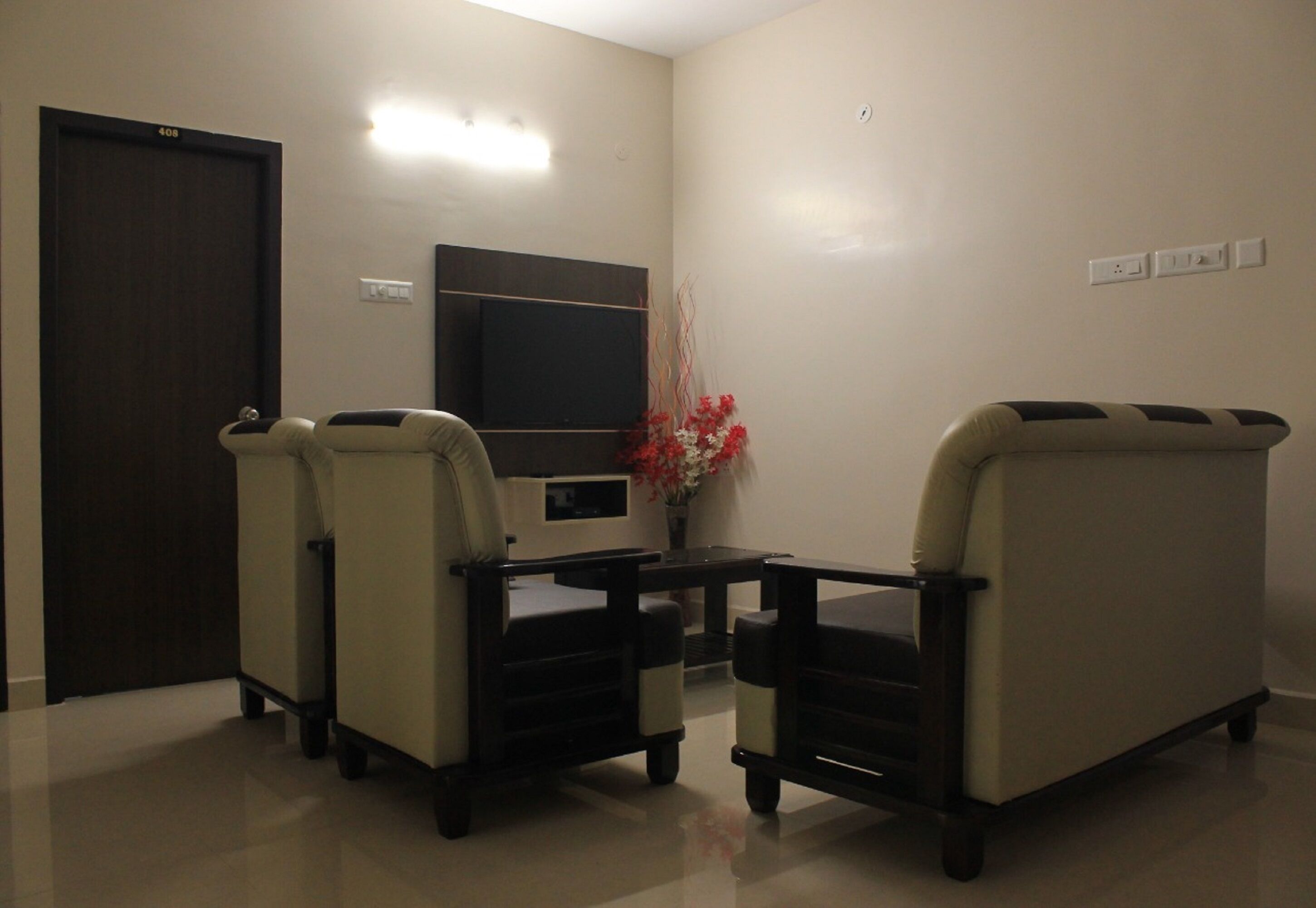 Um quarto com dois sofás, uma televisão, uma mesinha e uma porta.