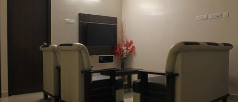 A room with two sofas, a TV, a small table, and a door.