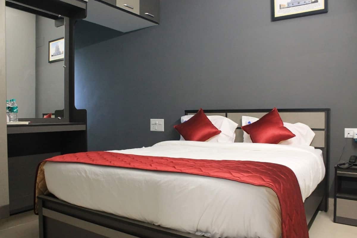 Quarto de hotel com cama, mesa de cabeceira, espelho e quadro na parede.
